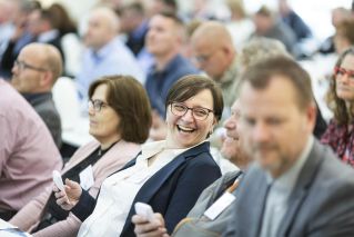Group of diverse adults smiling and engaging during an indoor business meeting, showcasing teamwork.